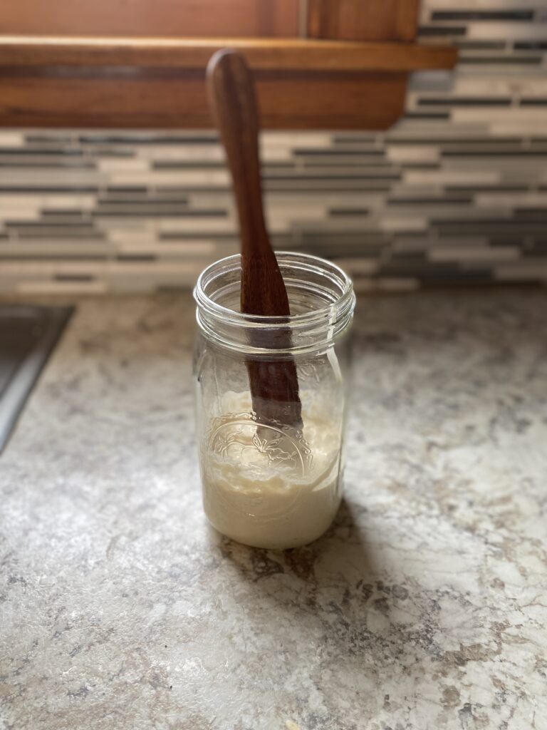 sourdough starter in glass jar with stirring stick