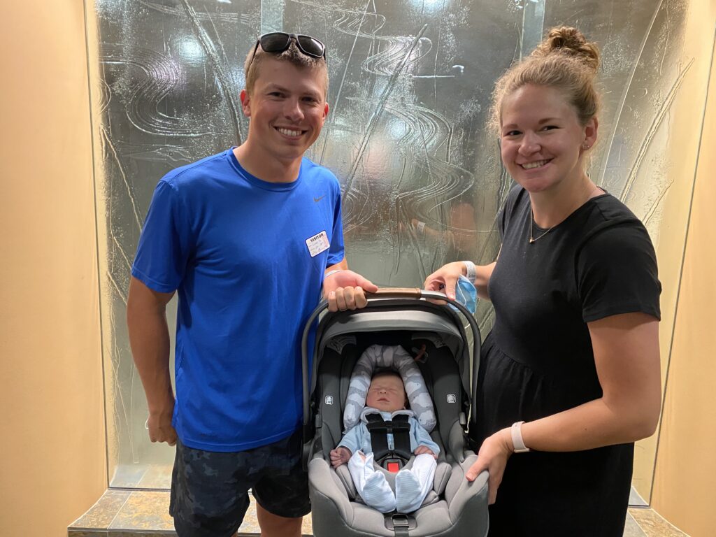first time mom and dad holding car seat with baby in it leaving the hospital