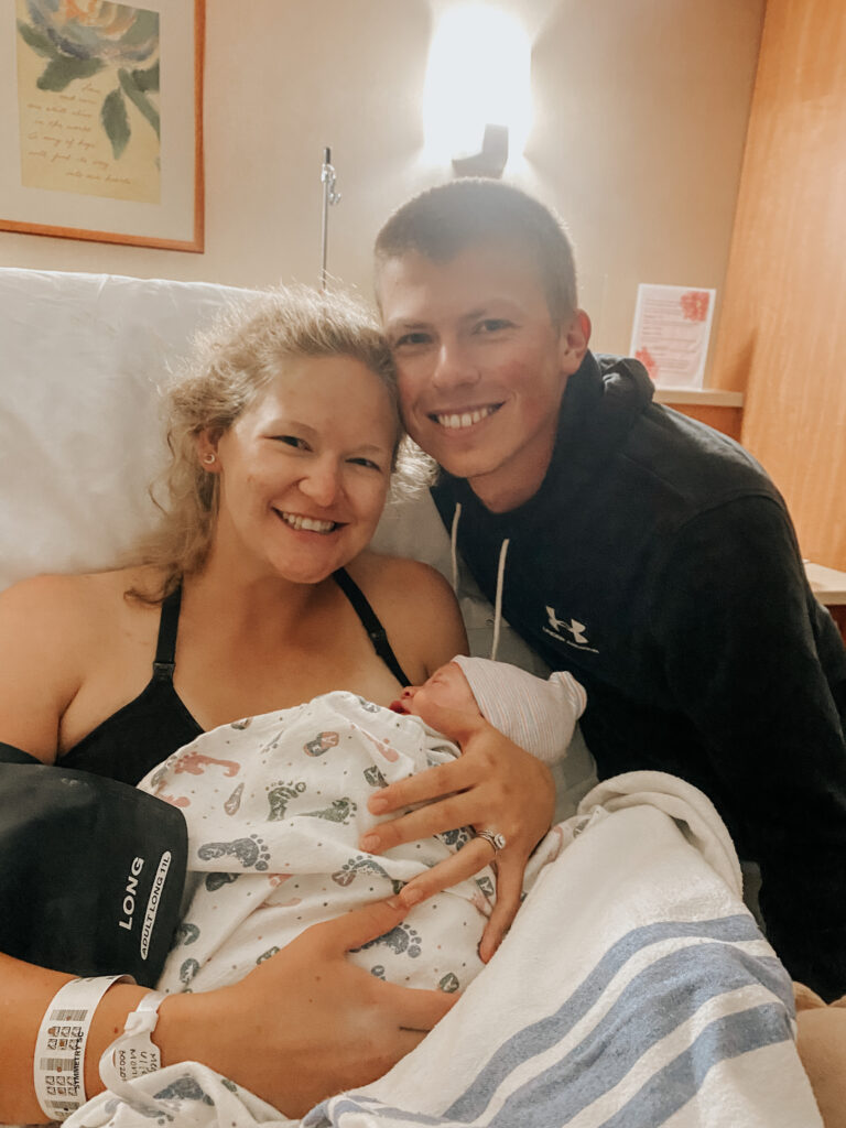 First time mom holding her newborn baby with husband by side